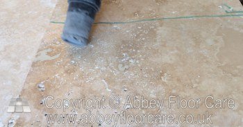 Dust being vacuumed from open travertine holes before filling
